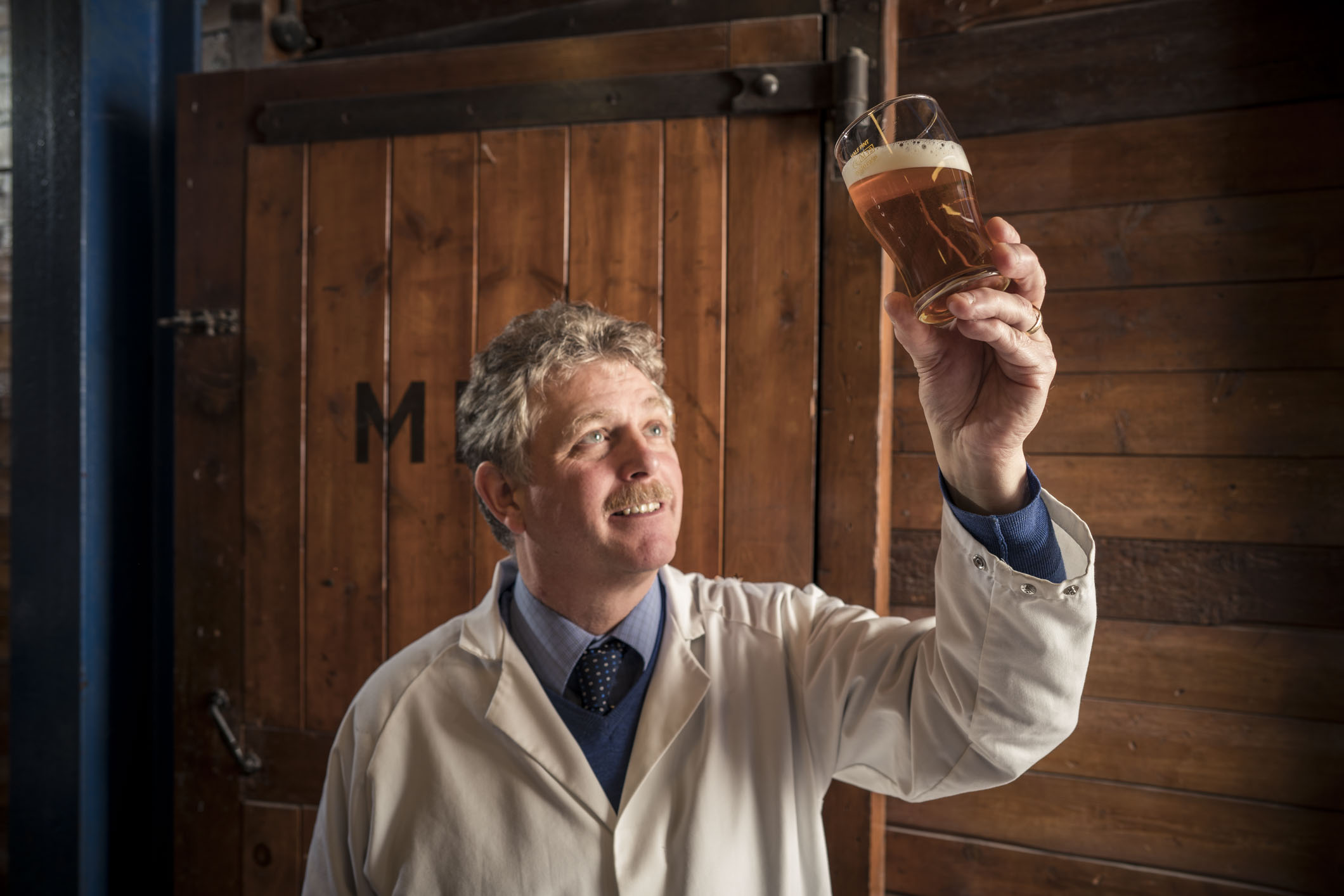 Andy Leman, Head Brewer of Timothy Taylor's holding up a pint of beer and smiling